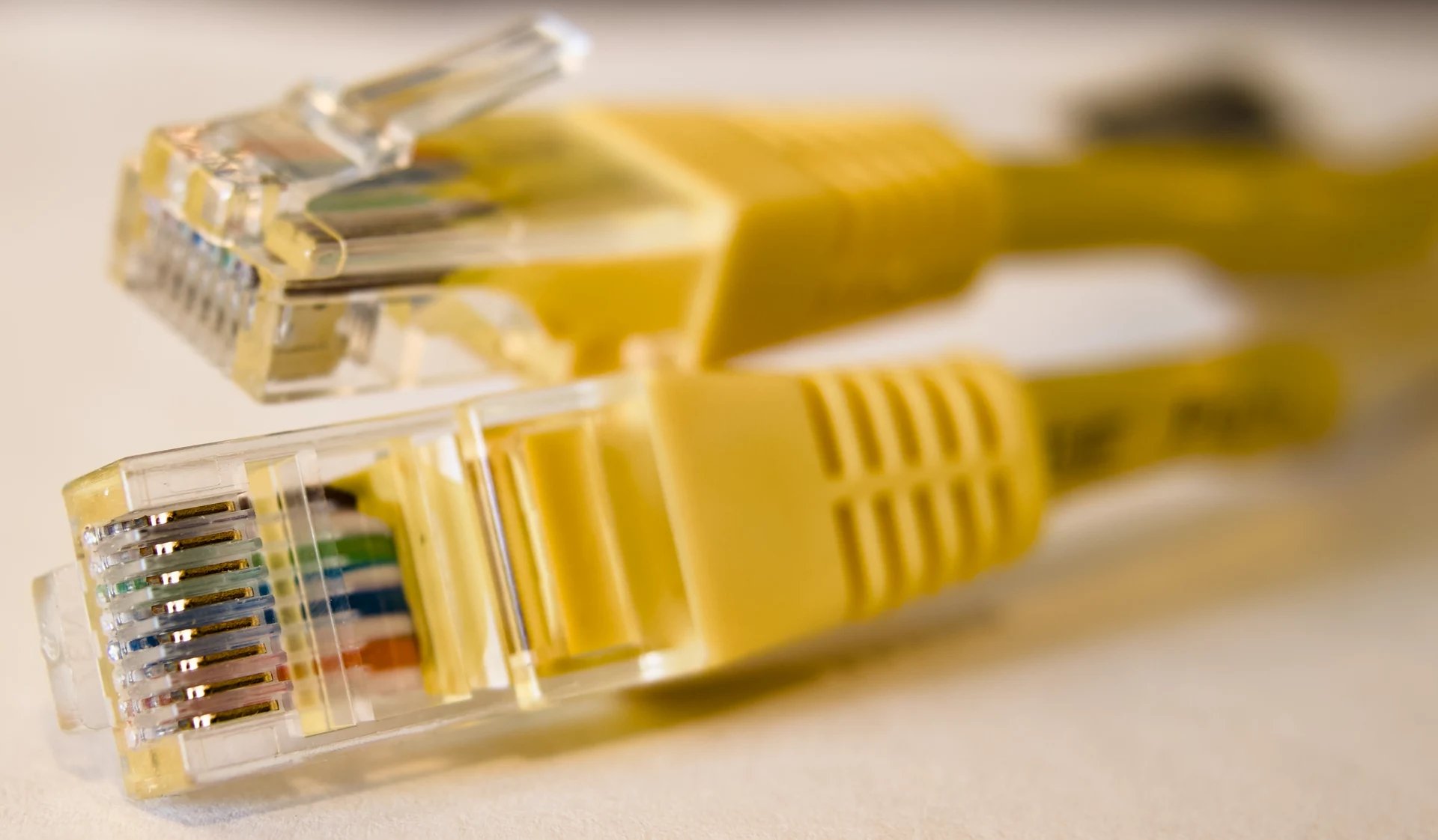 Two yellow ethernet cable plugs lying on a pale surface.